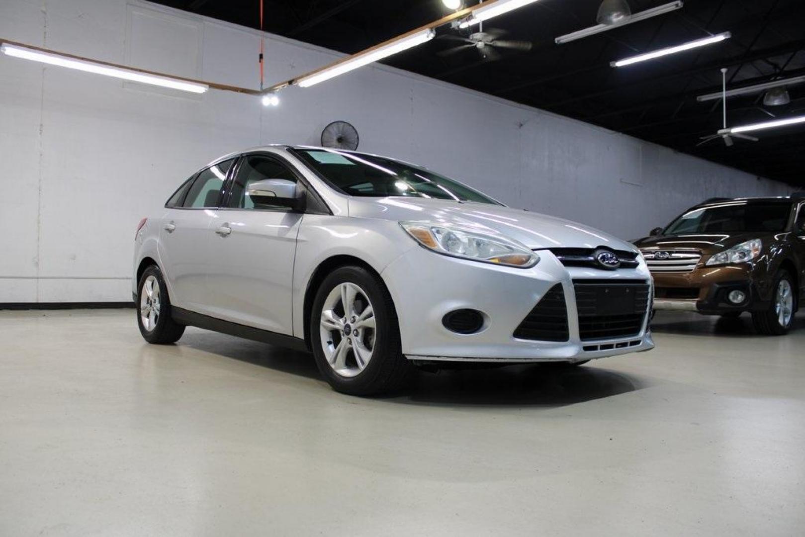 2014 Ingot Silver Metallic /Charcoal/Tangerine Scream Ford Focus SE (1FADP3F28EL) with an I4 engine, Automatic transmission, located at 15300 Midway Rd., Addison, TX, 75001, (972) 702-0011, 32.958321, -96.838074 - HOME OF THE NO HAGGLE PRICE - WHOLESALE PRICES TO THE PUBLIC!! Focus SE, 4D Sedan, I4, FWD, Silver, Charcoal/Tangerine Scream Cloth. Odometer is 60508 miles below market average!<br><br>Silver 2014 Ford Focus SE<br><br>26/36 City/Highway MPG<br><br>Awards:<br> * 2014 IIHS Top Safety Pick * 2014 K - Photo#1