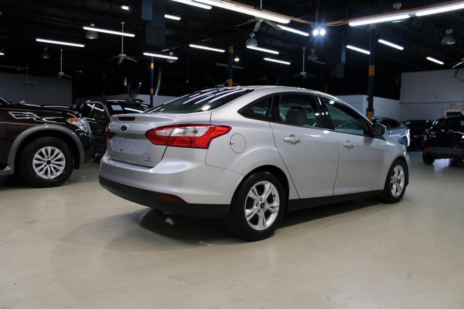 2014 Ingot Silver Metallic /Charcoal/Tangerine Scream Ford Focus SE (1FADP3F28EL) with an I4 engine, Automatic transmission, located at 15300 Midway Rd., Addison, TX, 75001, (972) 702-0011, 32.958321, -96.838074 - HOME OF THE NO HAGGLE PRICE - WHOLESALE PRICES TO THE PUBLIC!! Focus SE, 4D Sedan, I4, FWD, Silver, Charcoal/Tangerine Scream Cloth. Odometer is 60508 miles below market average!<br><br>Silver 2014 Ford Focus SE<br><br>26/36 City/Highway MPG<br><br>Awards:<br> * 2014 IIHS Top Safety Pick * 2014 K - Photo#2